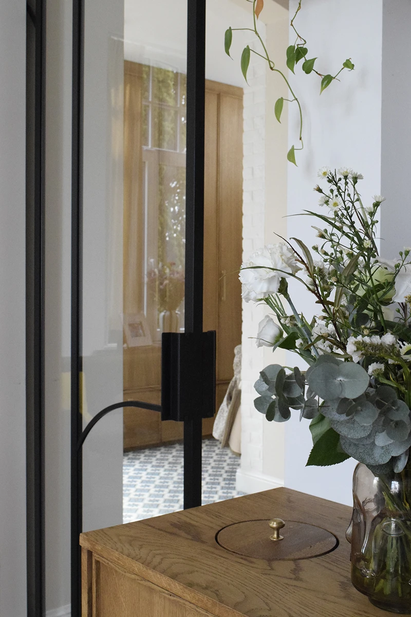 Aménagement intérieur avec verrière noire et mobilier en bois sur mesure